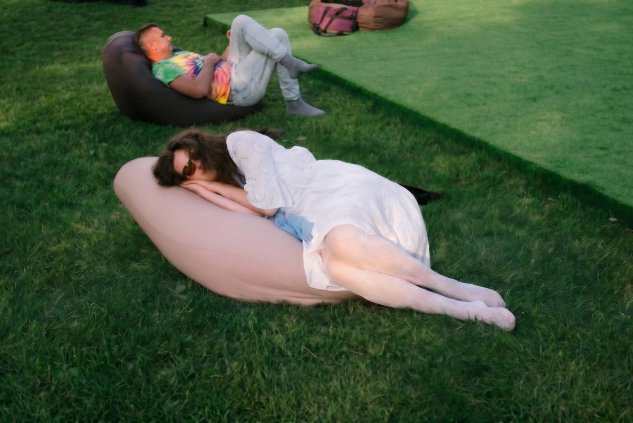 Man and woman relaxing on bean bags in a park, illustrating an article about whether sex or masturbation is more beneficial for men's health